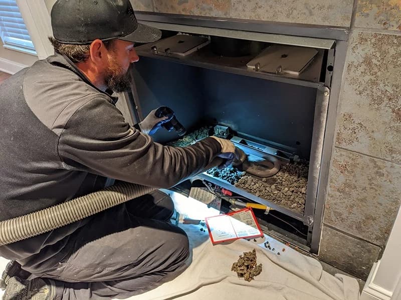 Certified technician inspecting and cleaning a fireplace